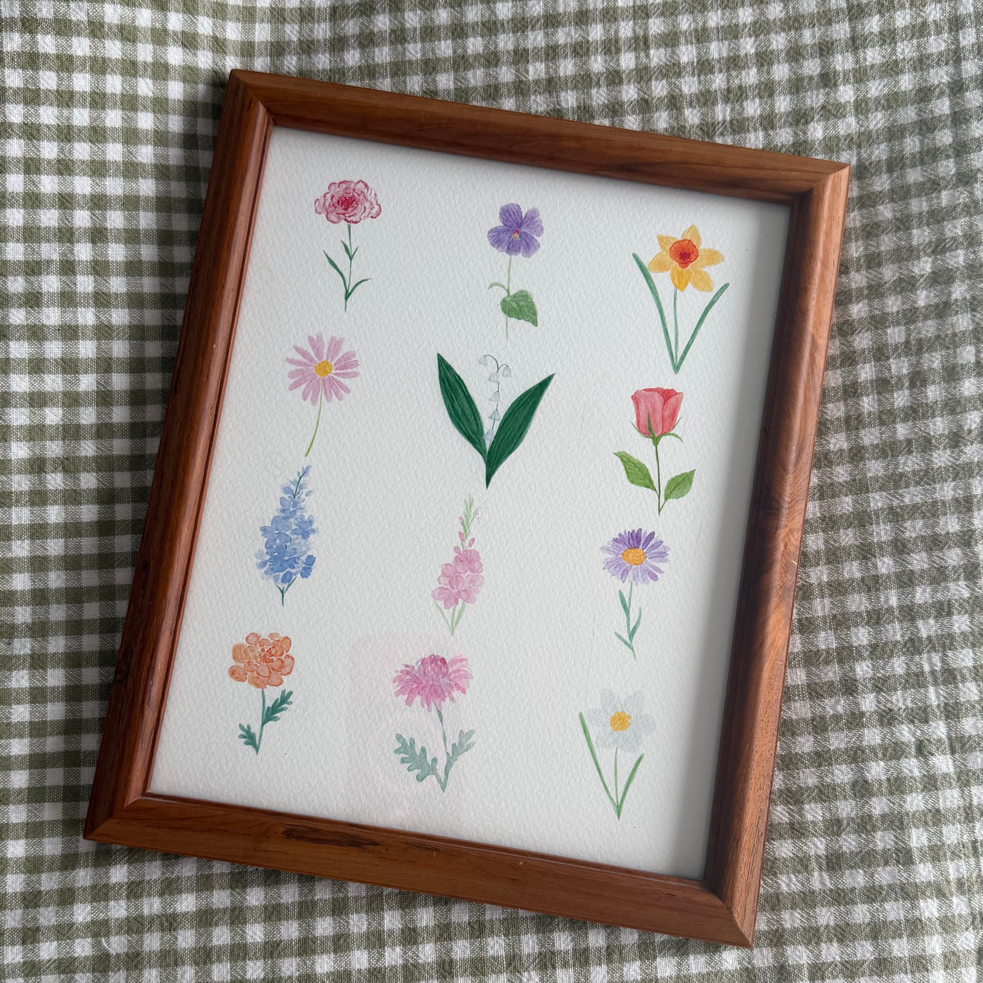Birth flower watercolor art print in wooden frame with a green checkered background.