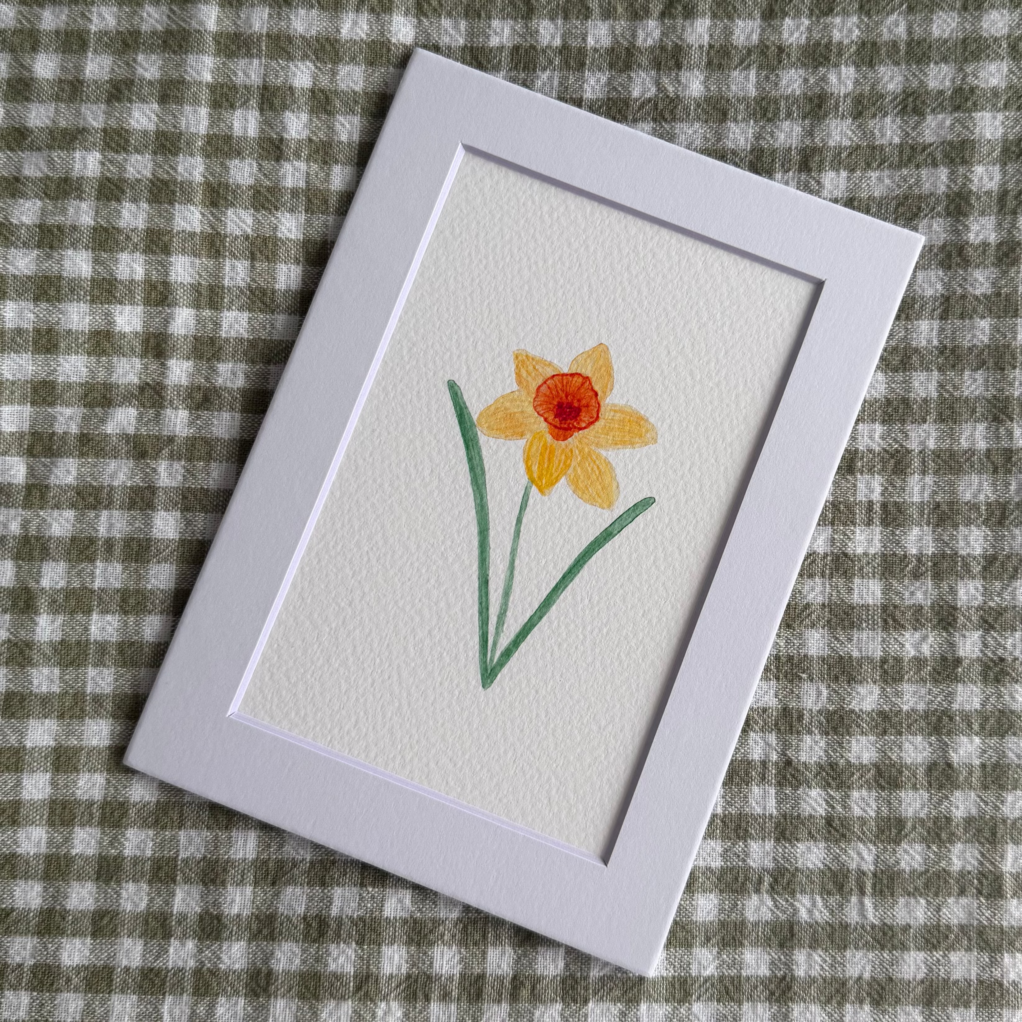 Small card with a yellow flower illustration on a checkered fabric background