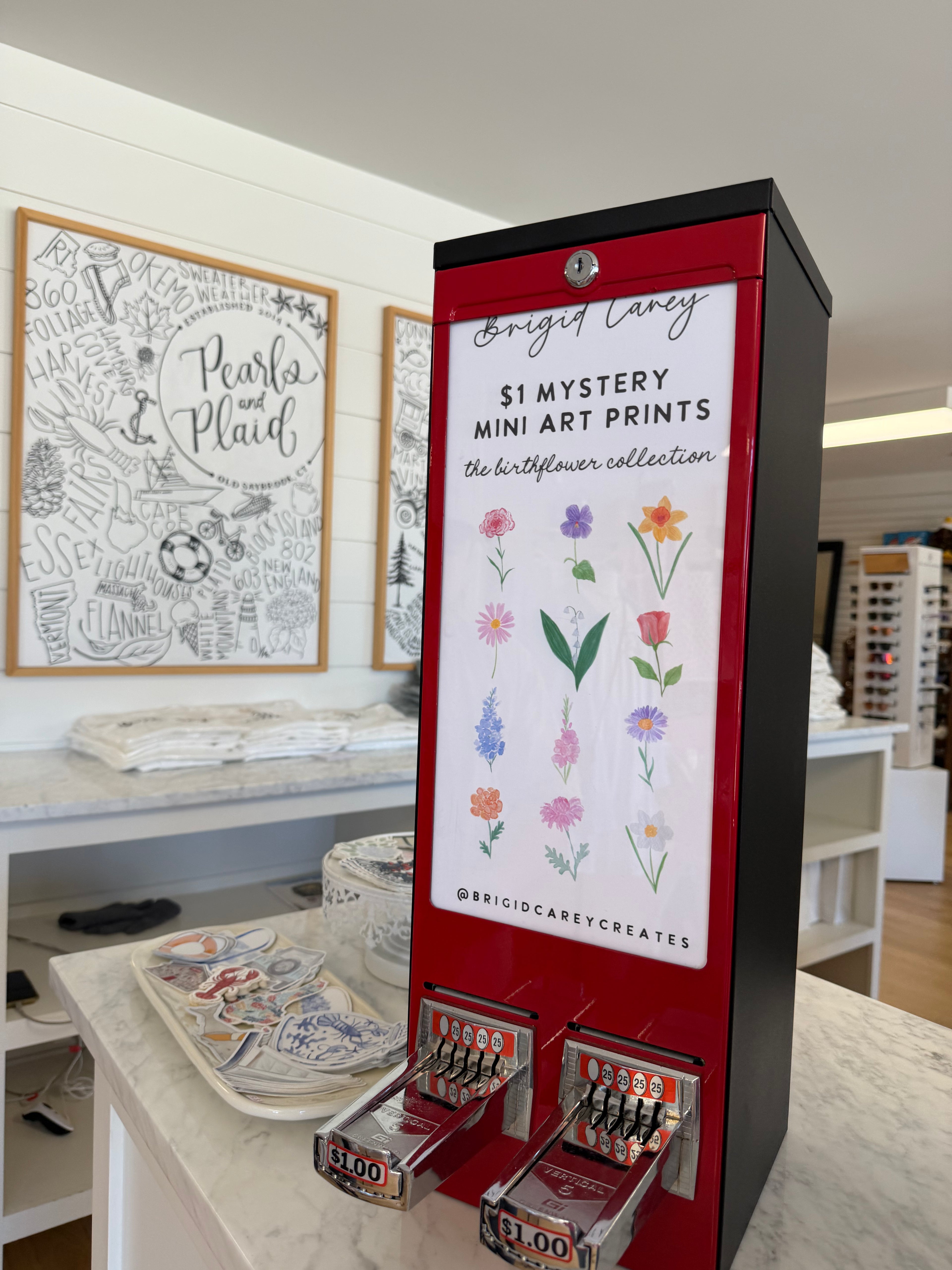Red vending machine with art prints on a counter in a store setting